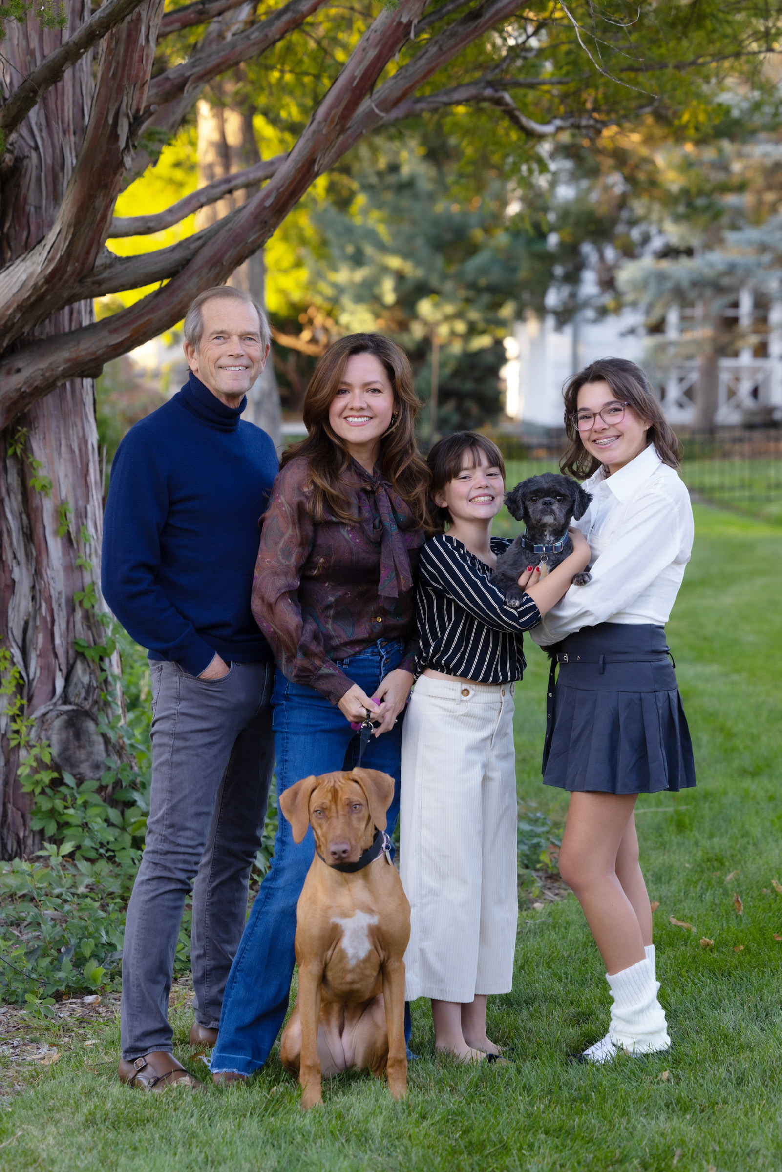 Family posing together outdoors with two dogs during a portrait session.