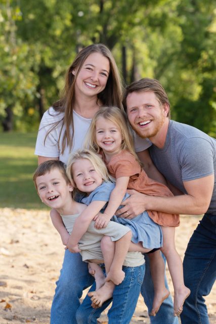 Parents smiling with their young children during an outdoor family portrait.