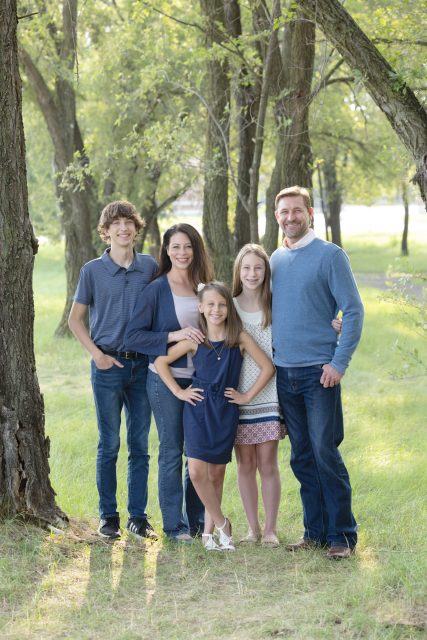 Family standing together in a park during an outdoor portrait session.