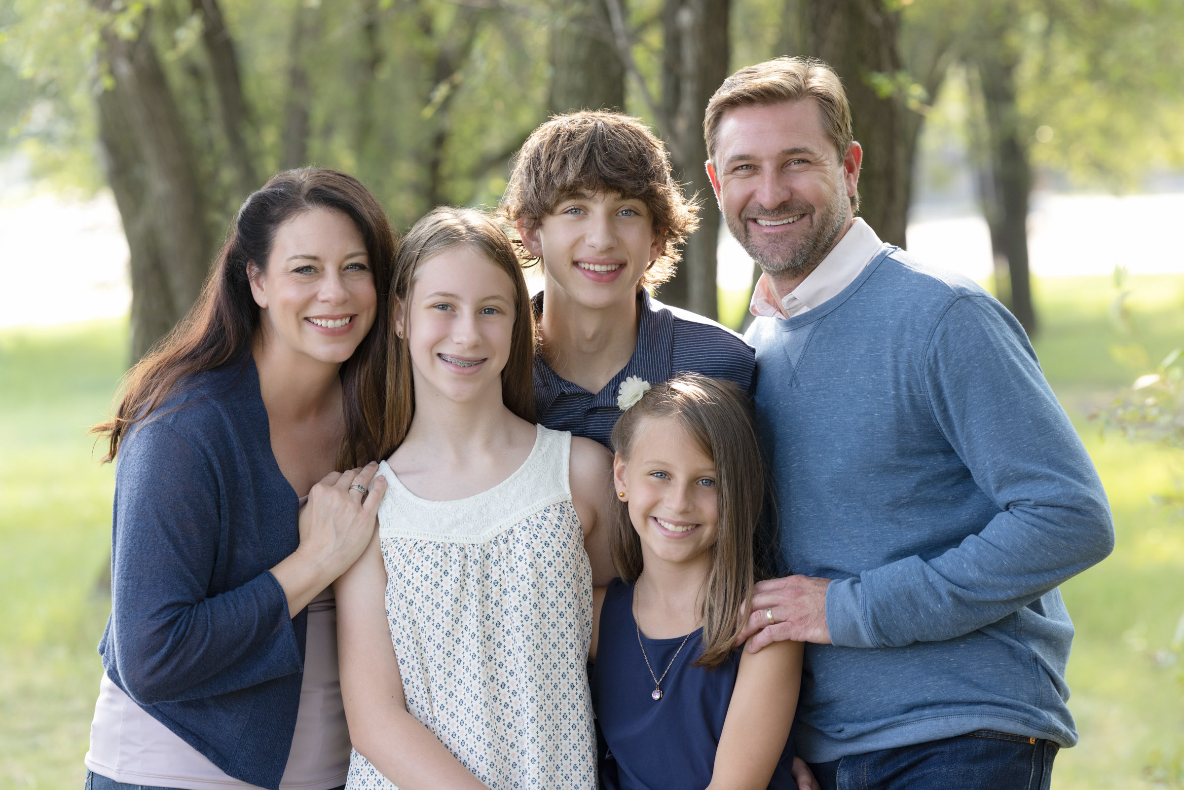 Family of five standing together outdoors during a portrait session.