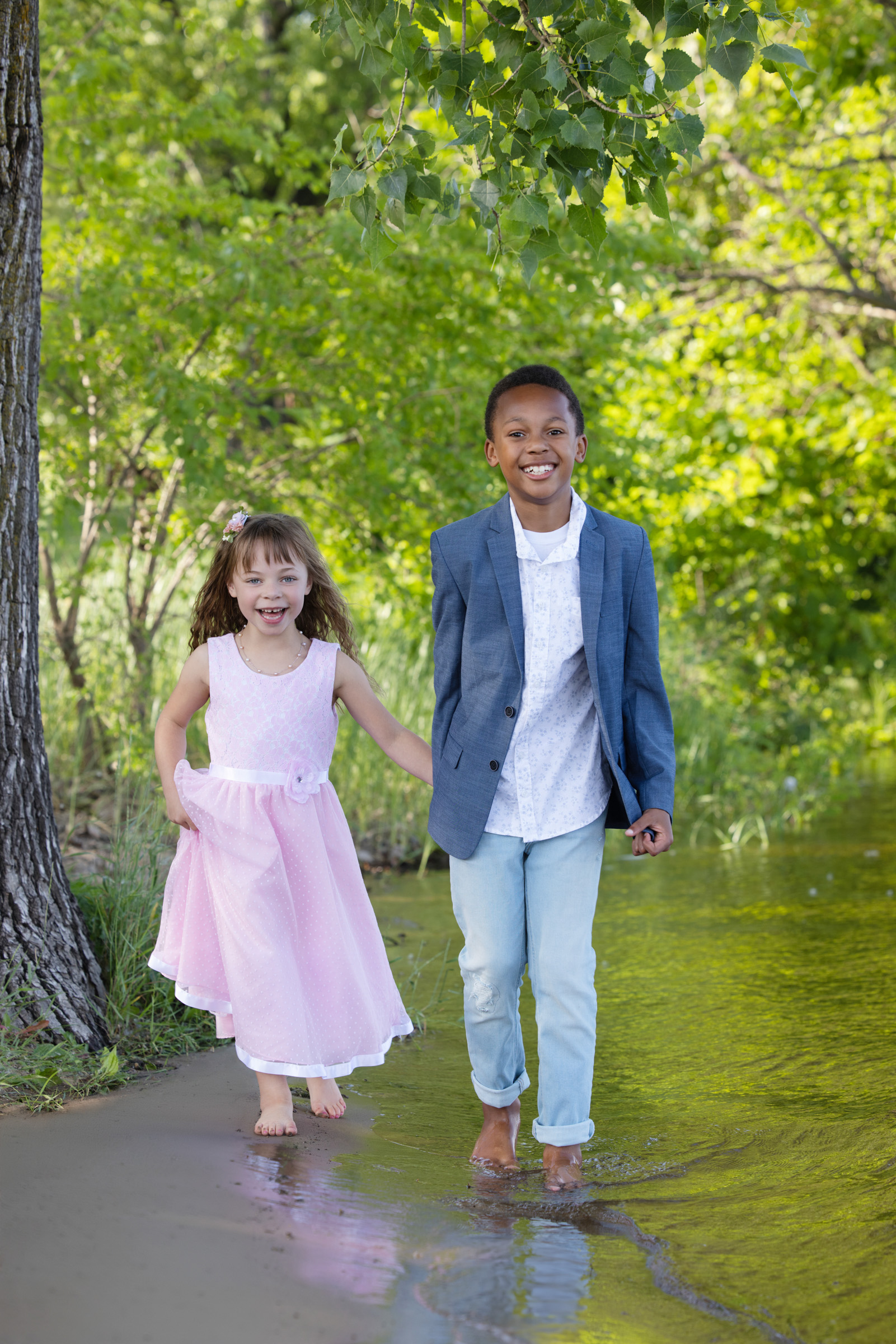 Brother and sister holding hands while walking together during an outdoor family portrait session.