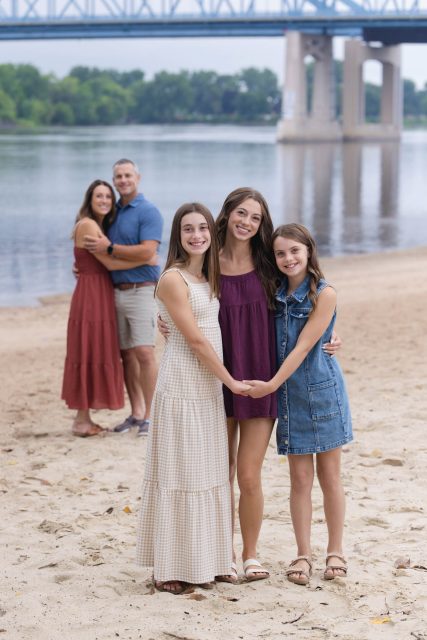 Family standing together on a sandy beach during an outdoor portrait session.