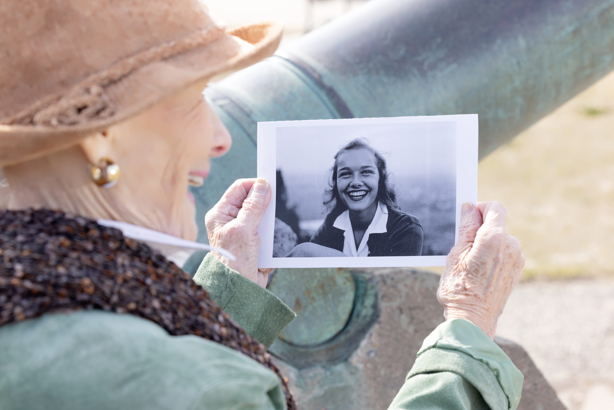Woman holding a printed portrait while looking at it outdoors.