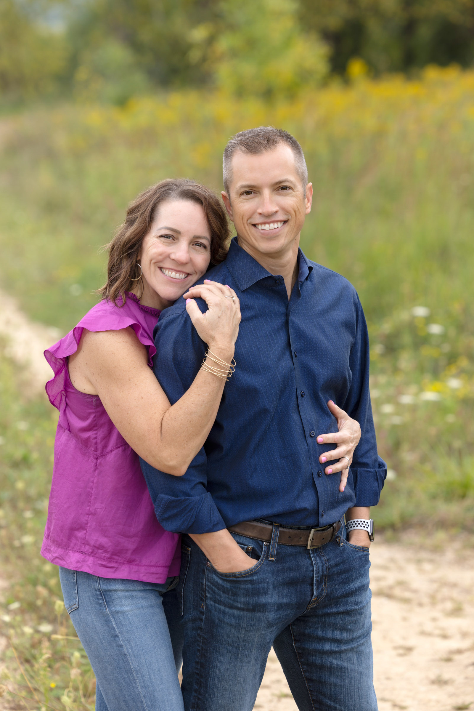 Parents embracing and smiling during an outdoor family portrait session.