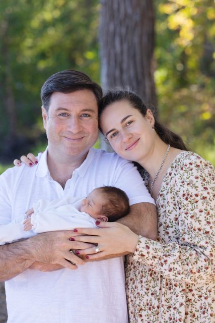 Parents holding their newborn baby during an outdoor family portrait session.