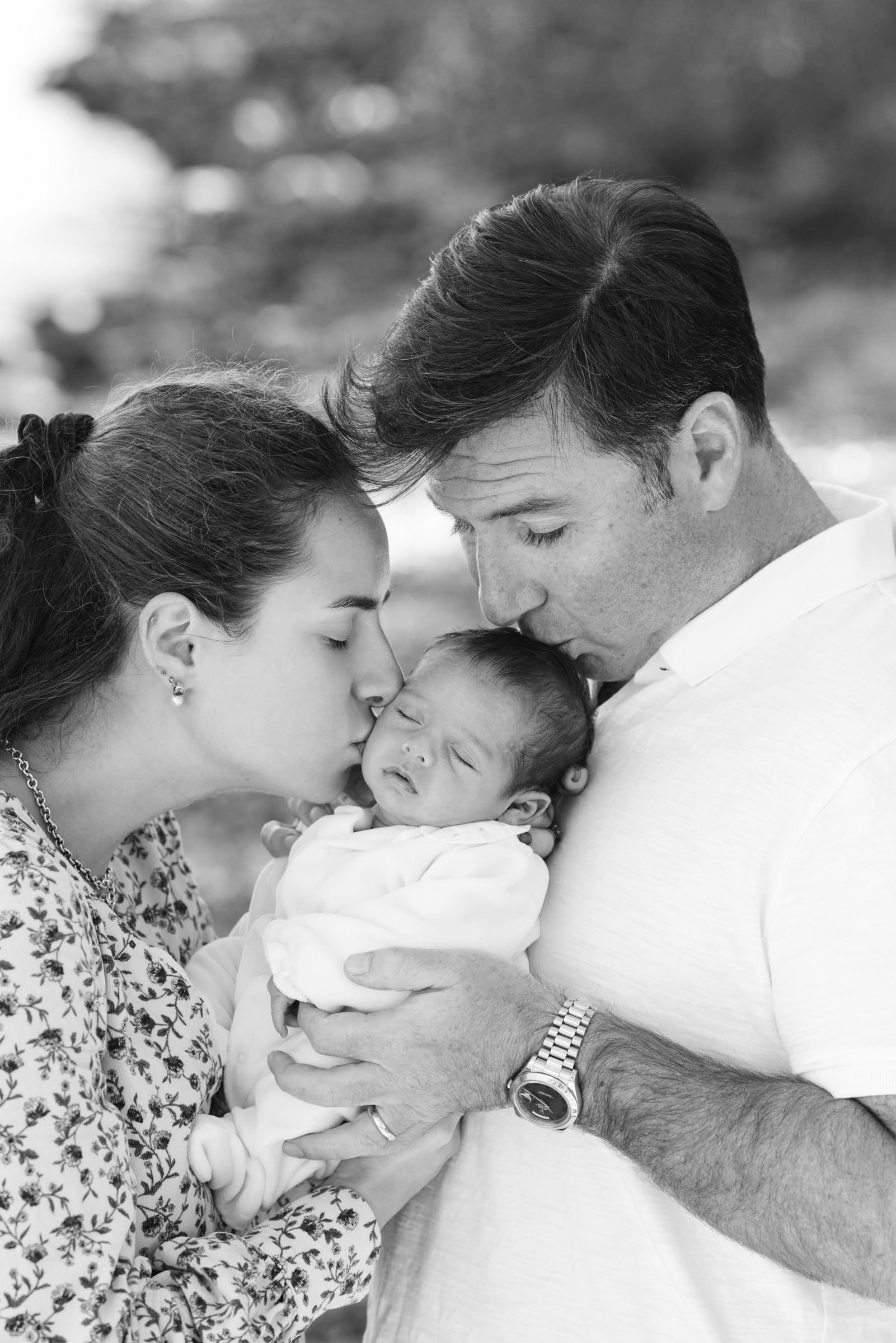 Parents holding their newborn baby close during a family portrait session.
