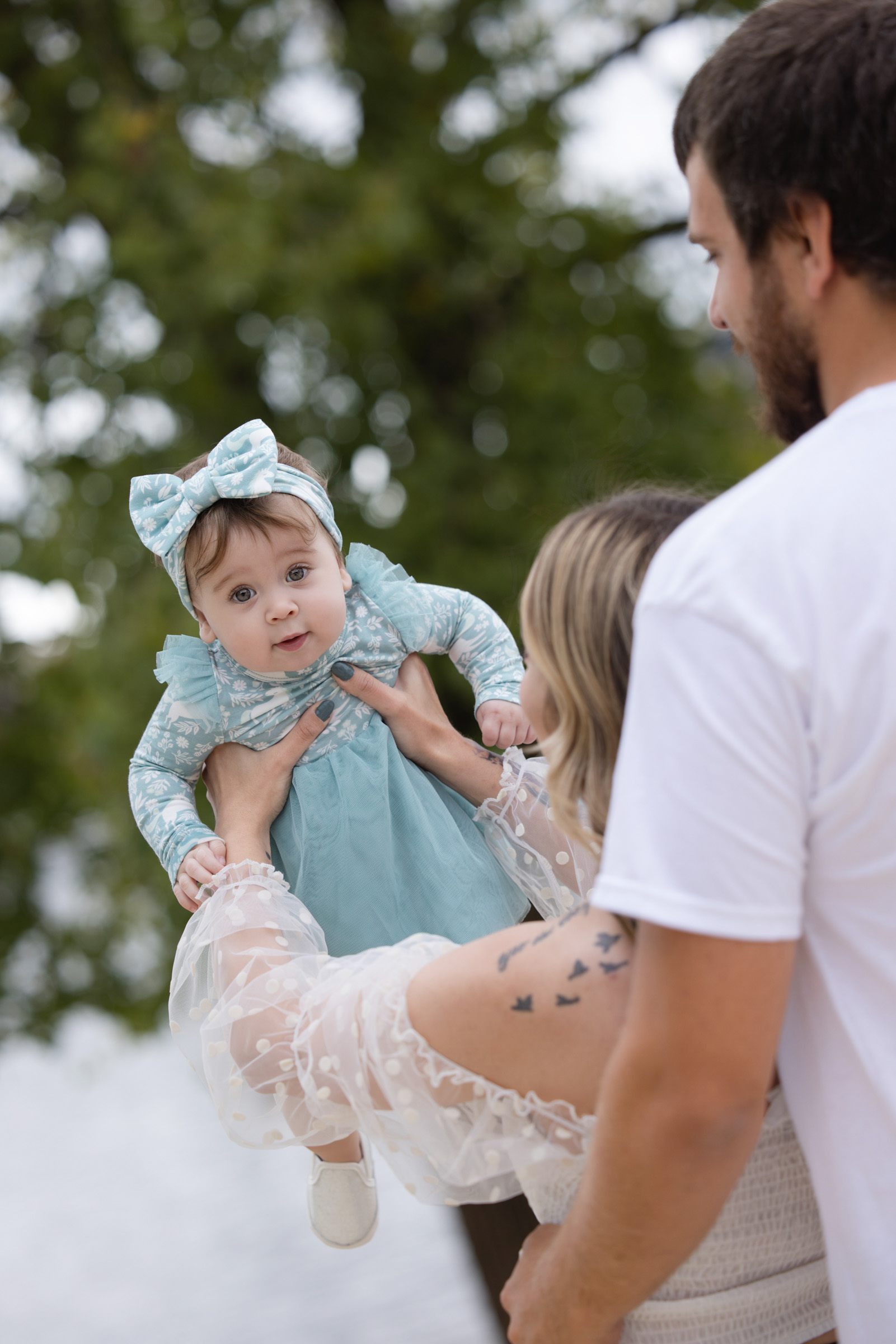 Parents lifting their baby into the air during an outdoor family portrait session.