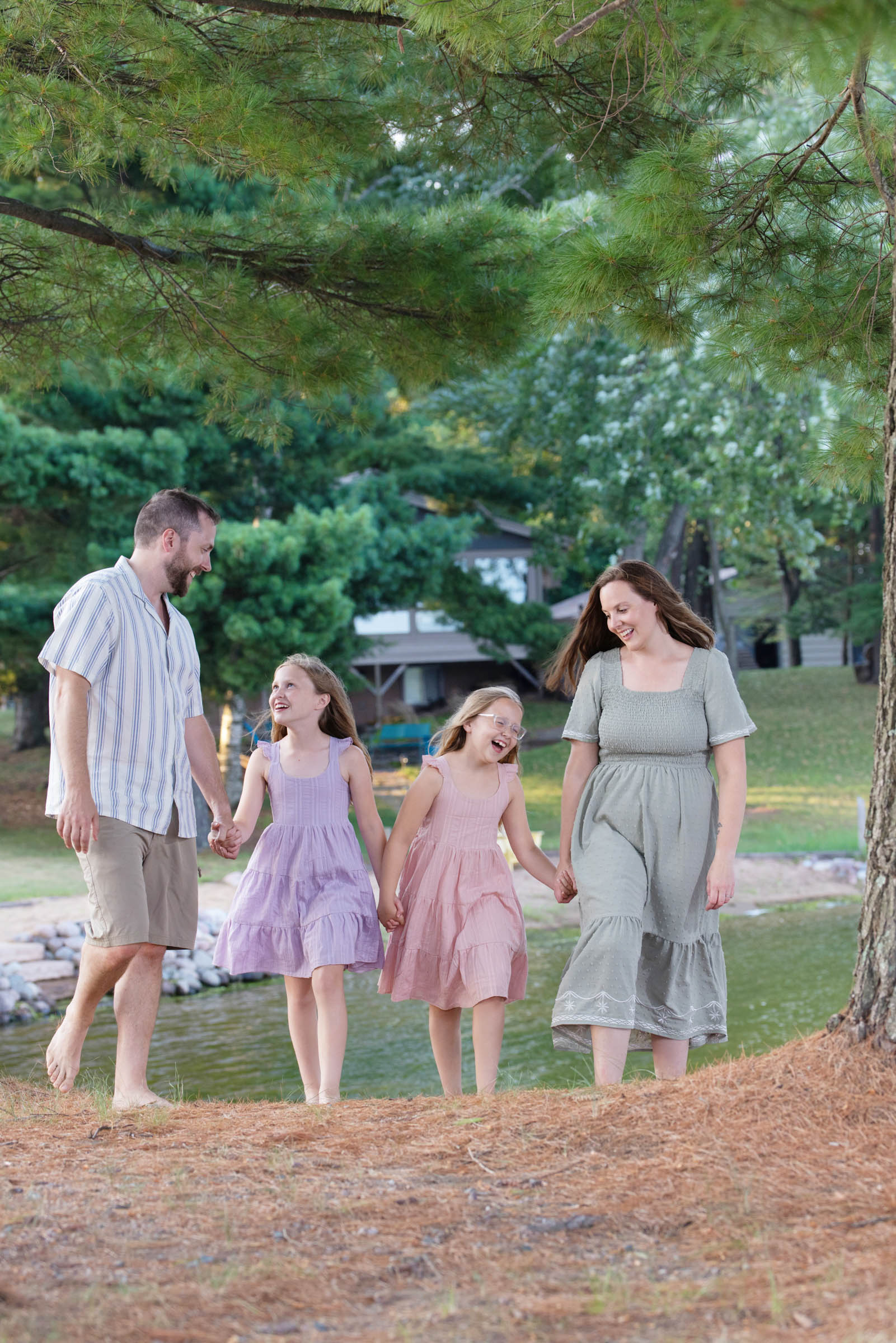 Parents walking hand in hand with their children through a park during an outdoor family portrait session.
