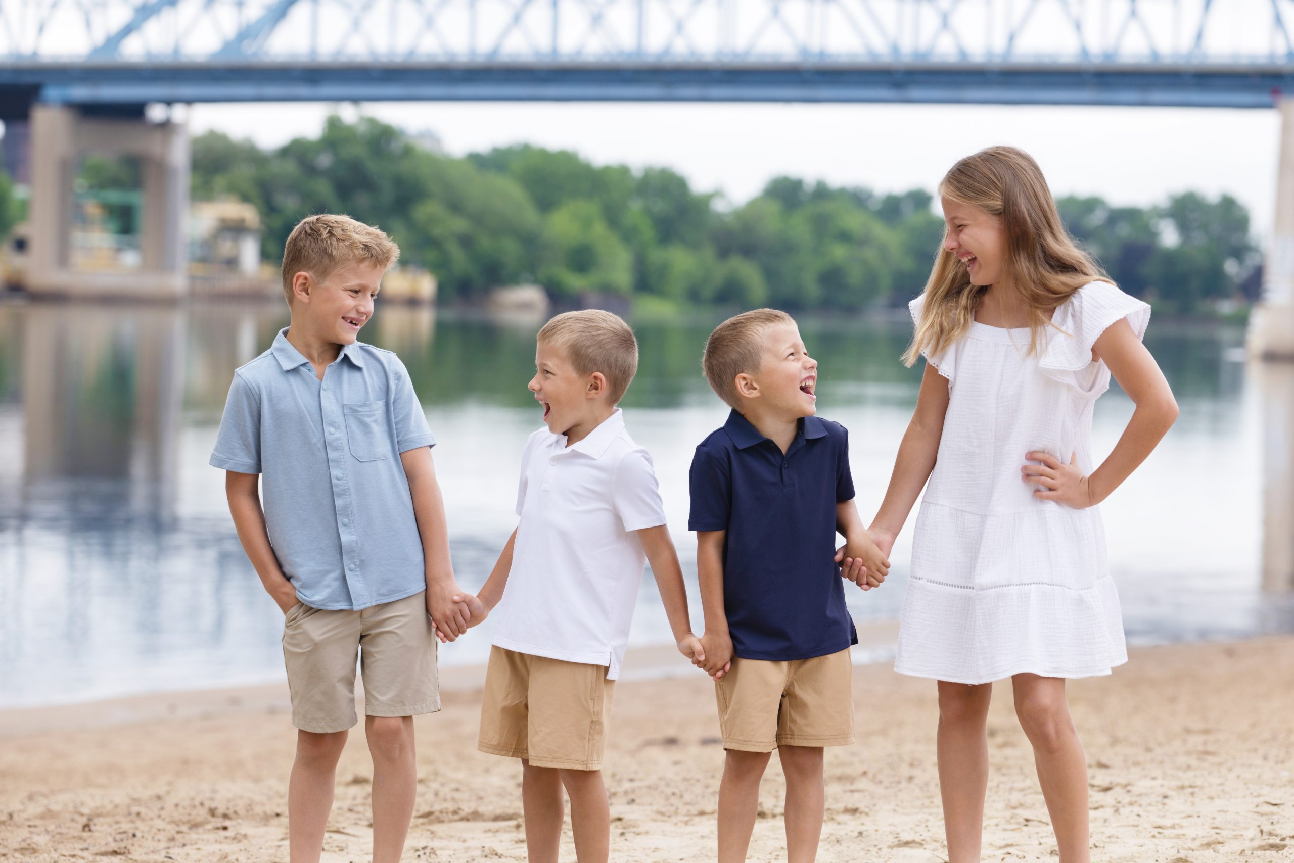 Children standing together on a beach during a family portrait session.