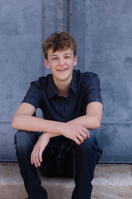 High school senior sitting outdoors during a portrait session.