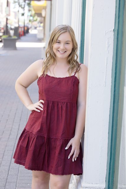 High school senior standing on a downtown sidewalk during a portrait session.