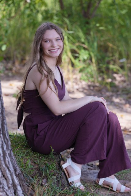 High school senior sitting outdoors during a portrait session.