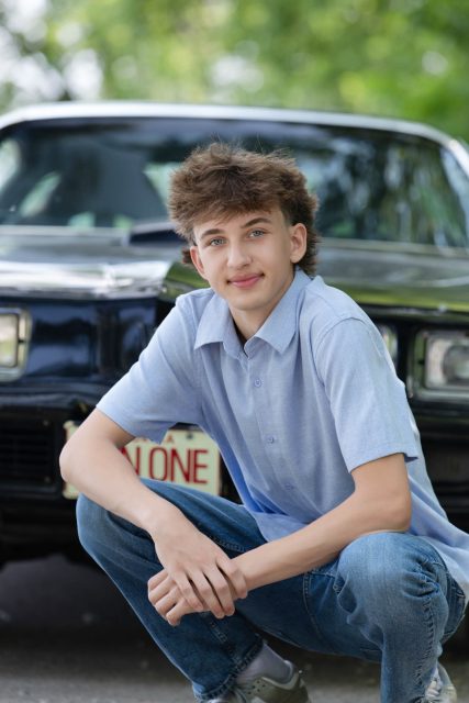 High school senior sitting in front of a vintage truck during an outdoor portrait session.