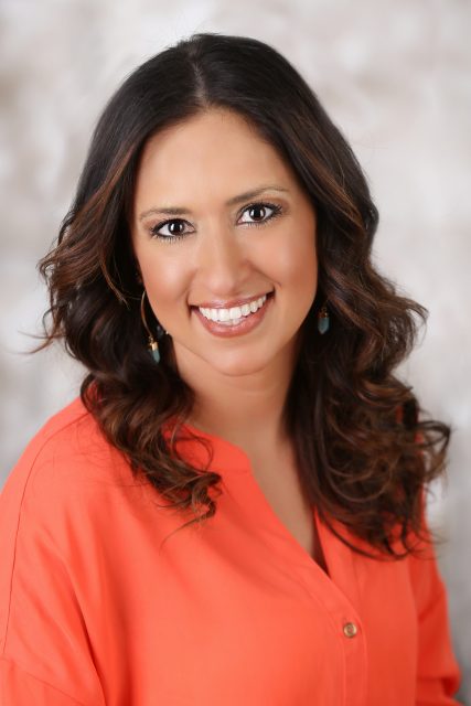 Professional headshot of a woman smiling toward the camera with a soft background.