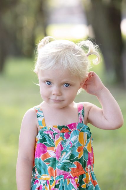 Young child standing outdoors and looking at the camera during a portrait session.