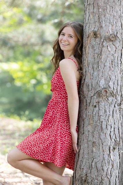High school senior standing beside a tree during an outdoor portrait session.