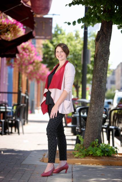 Professional portrait of a woman standing on a downtown sidewalk in business attire.