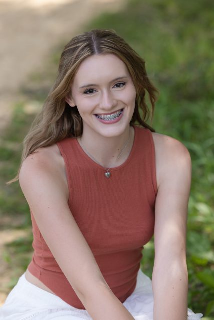 High school senior smiling toward the camera during an outdoor portrait session.