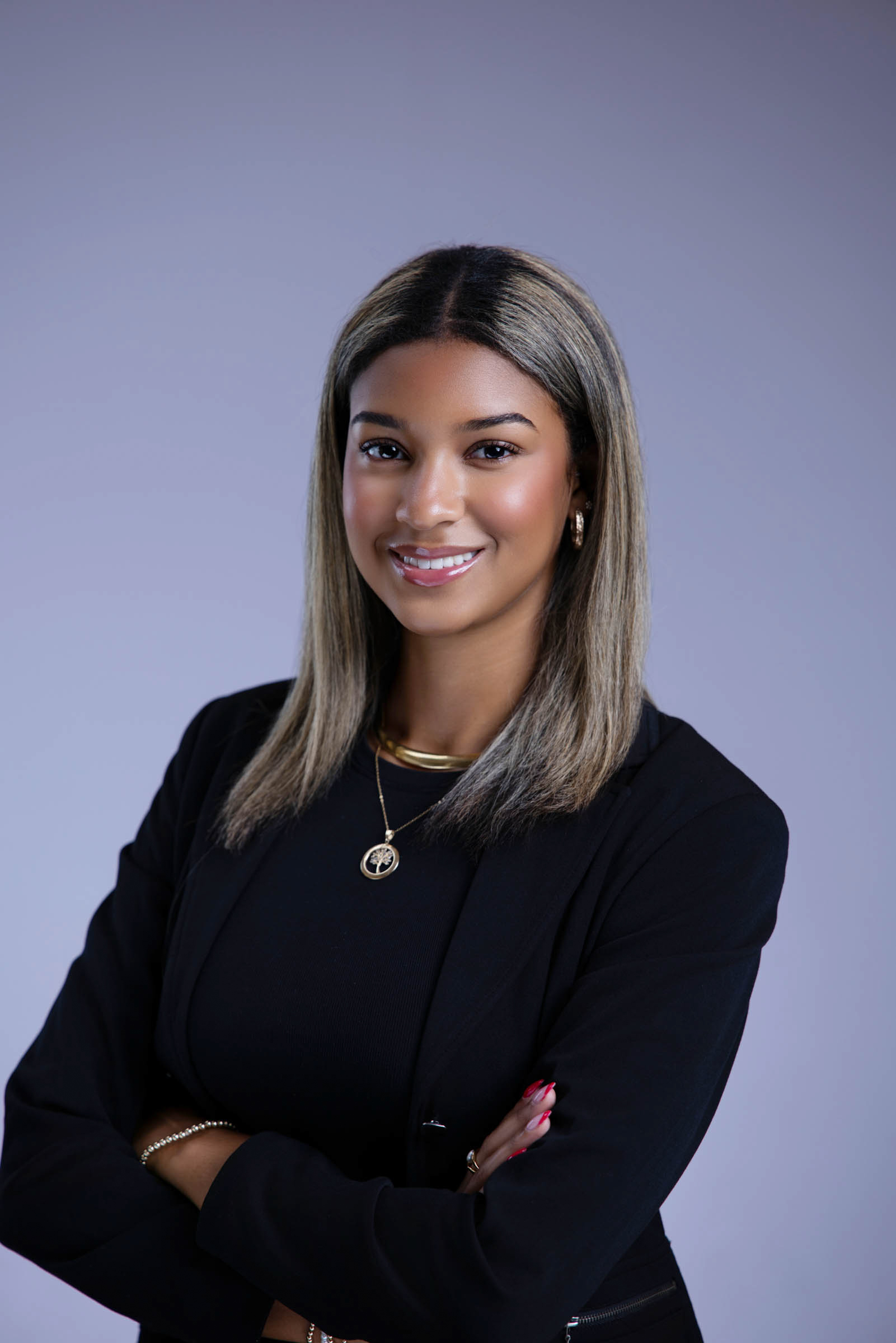 Professional studio headshot of a woman wearing a black blazer and smiling toward the camera.
