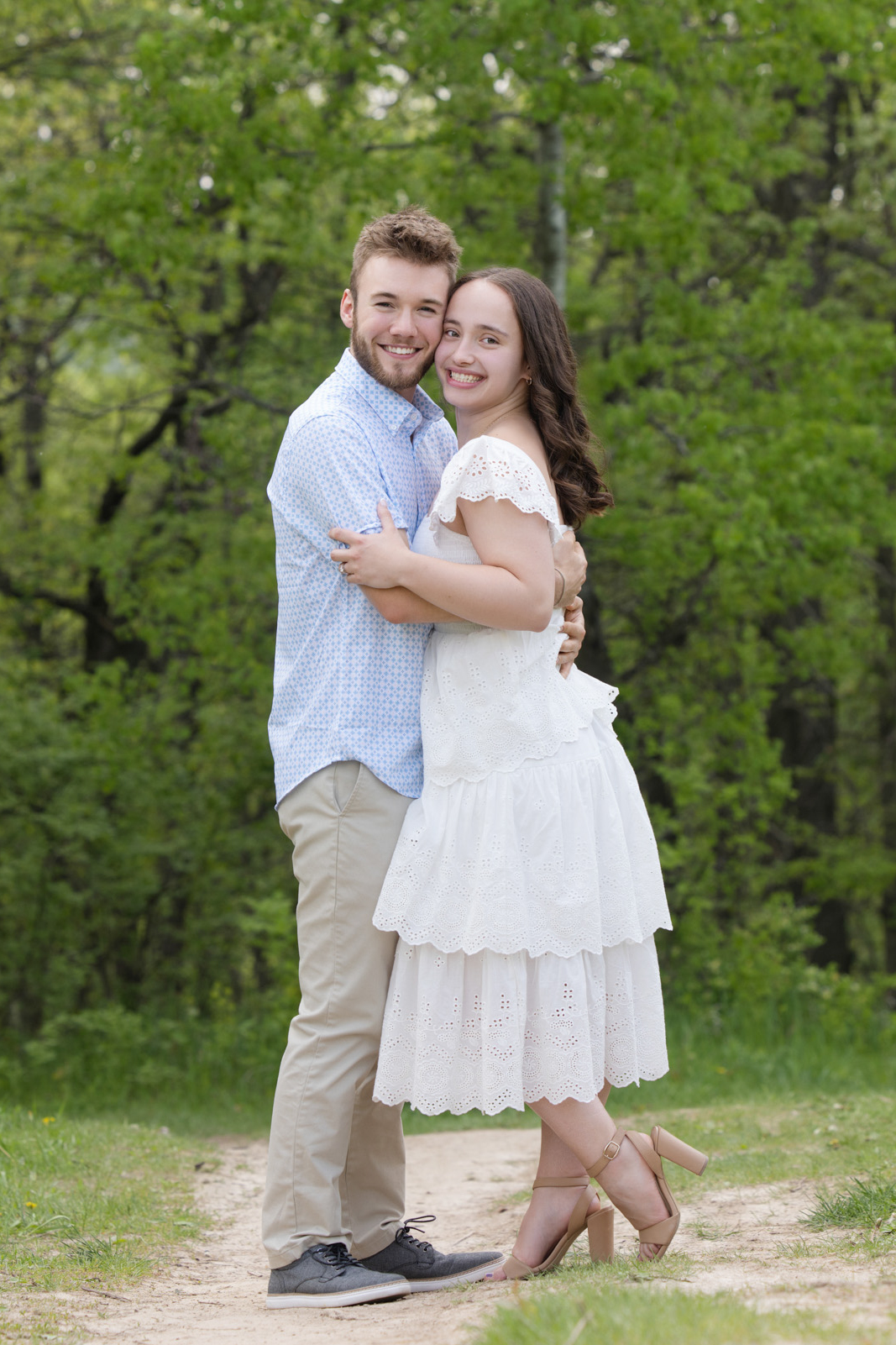 Engaged couple standing together and embracing outdoors during their engagement session.