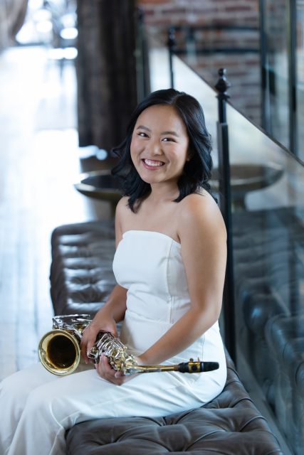 High school senior smiling while holding a musical instrument during a portrait session.