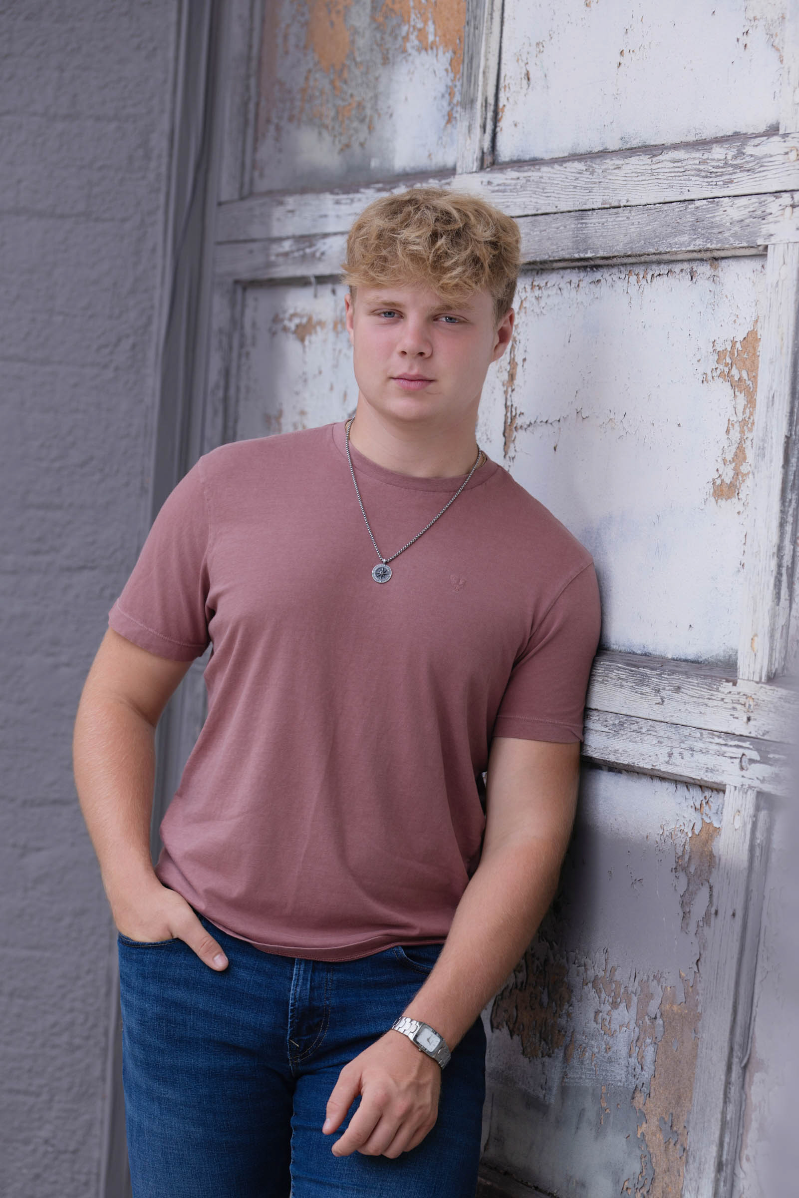 High school senior leaning against a brick wall during an outdoor portrait session.