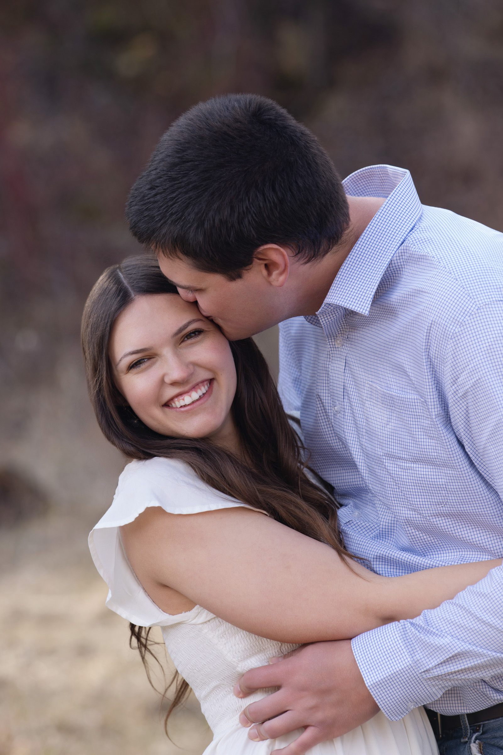 Engaged couple smiling together during an outdoor engagement portrait session.