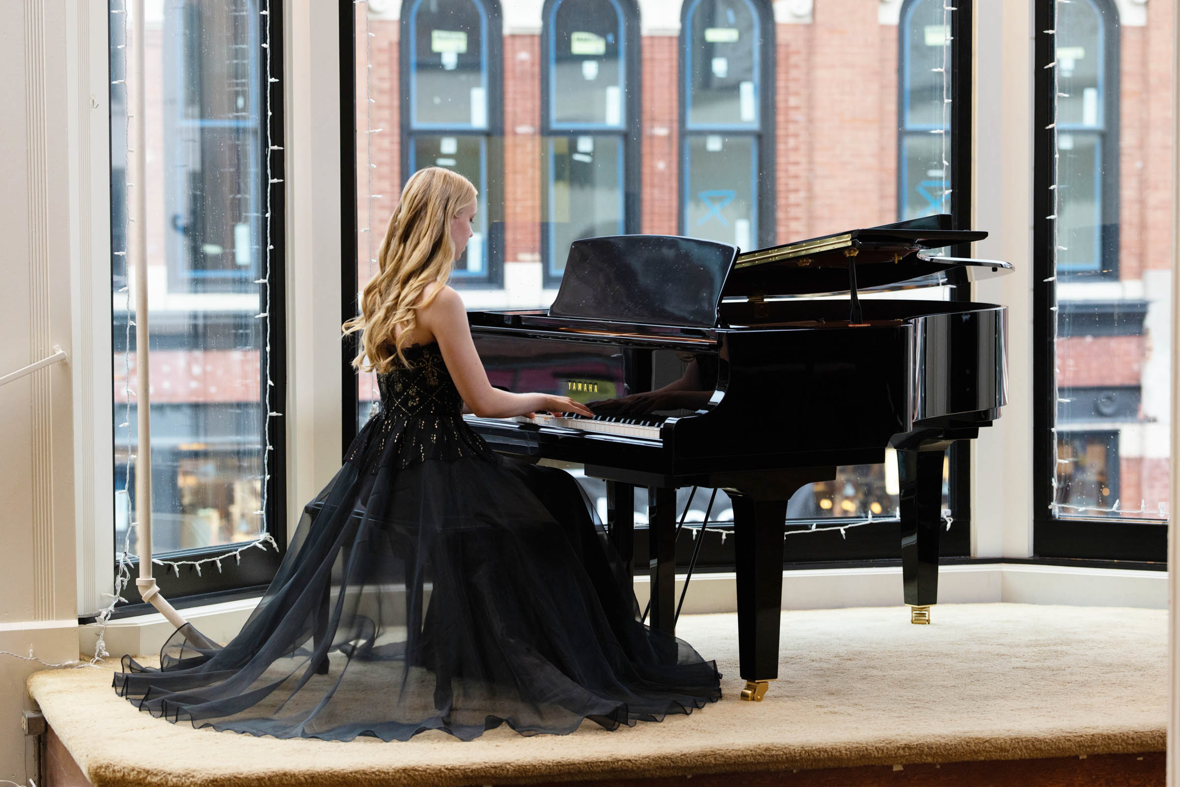High school senior seated at a grand piano during a portrait session.