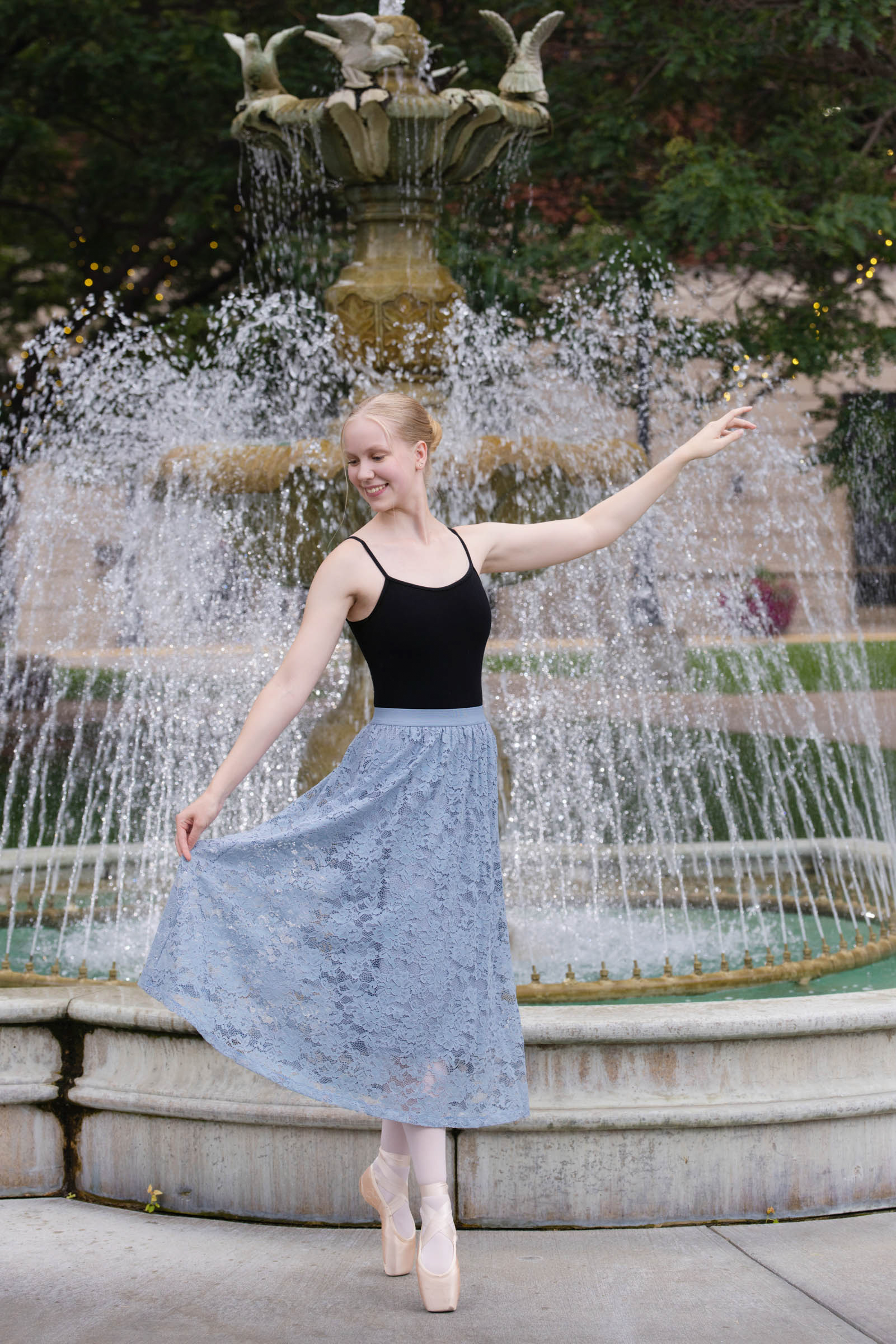 High school senior posing in front of a fountain during an outdoor senior portrait session.