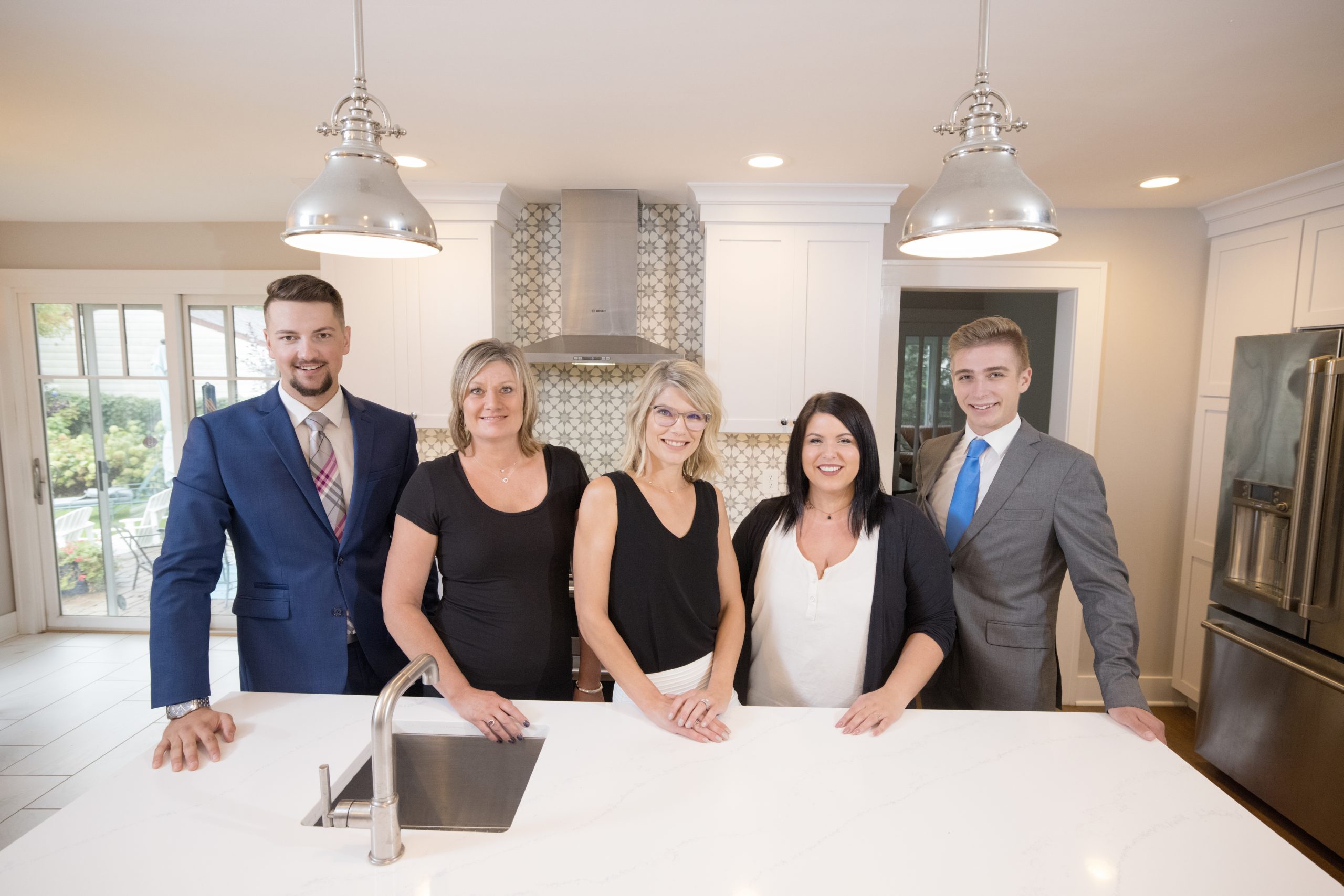 Business team standing together inside a modern kitchen during a team portrait session.