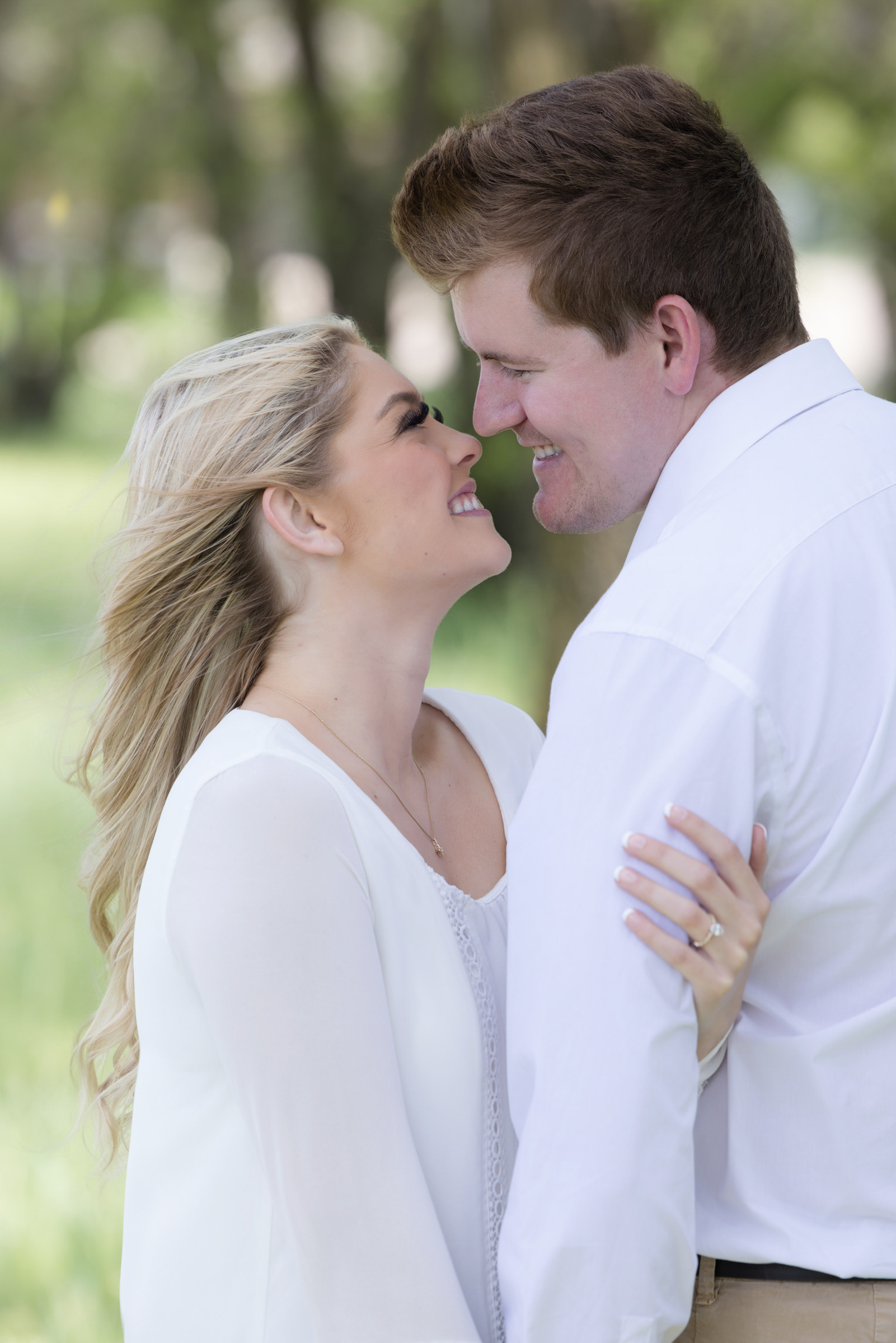 Engaged couple smiling at each other during an outdoor engagement portrait session.