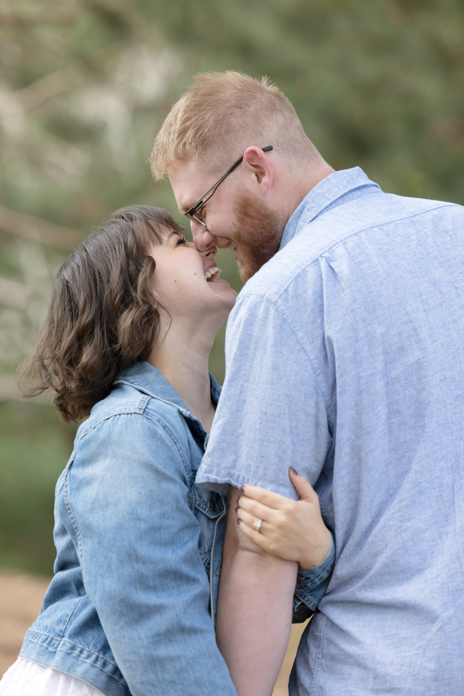 Engaged couple smiling and laughing together during their engagement portrait session.