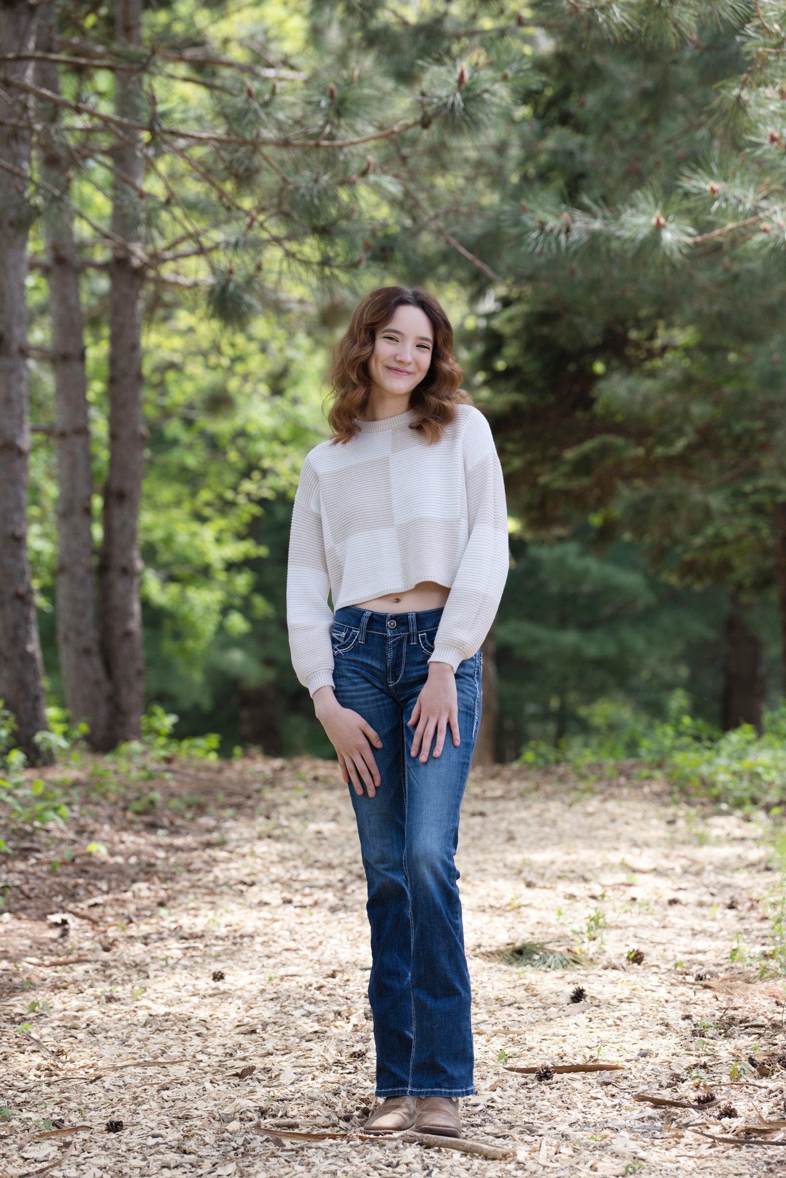 High school senior standing on a wooded path during an outdoor portrait session.