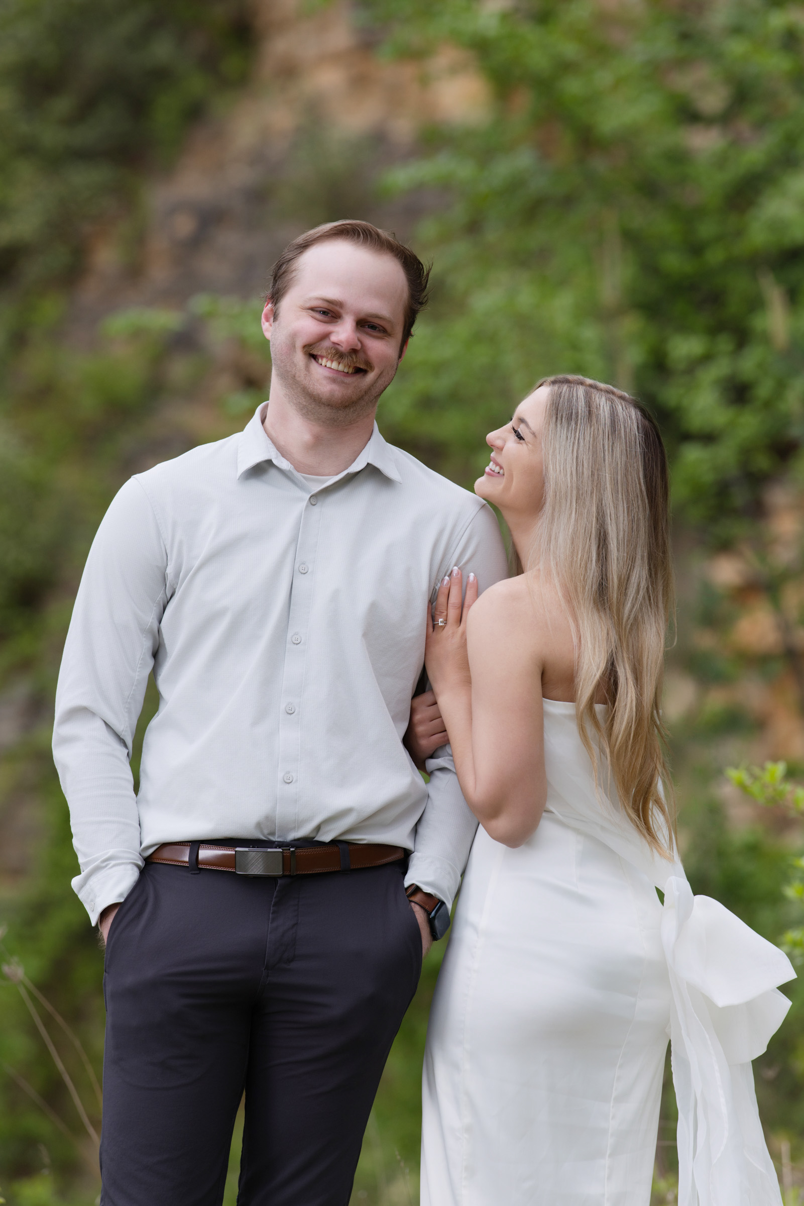 Engaged couple smiling together outdoors during their engagement session.