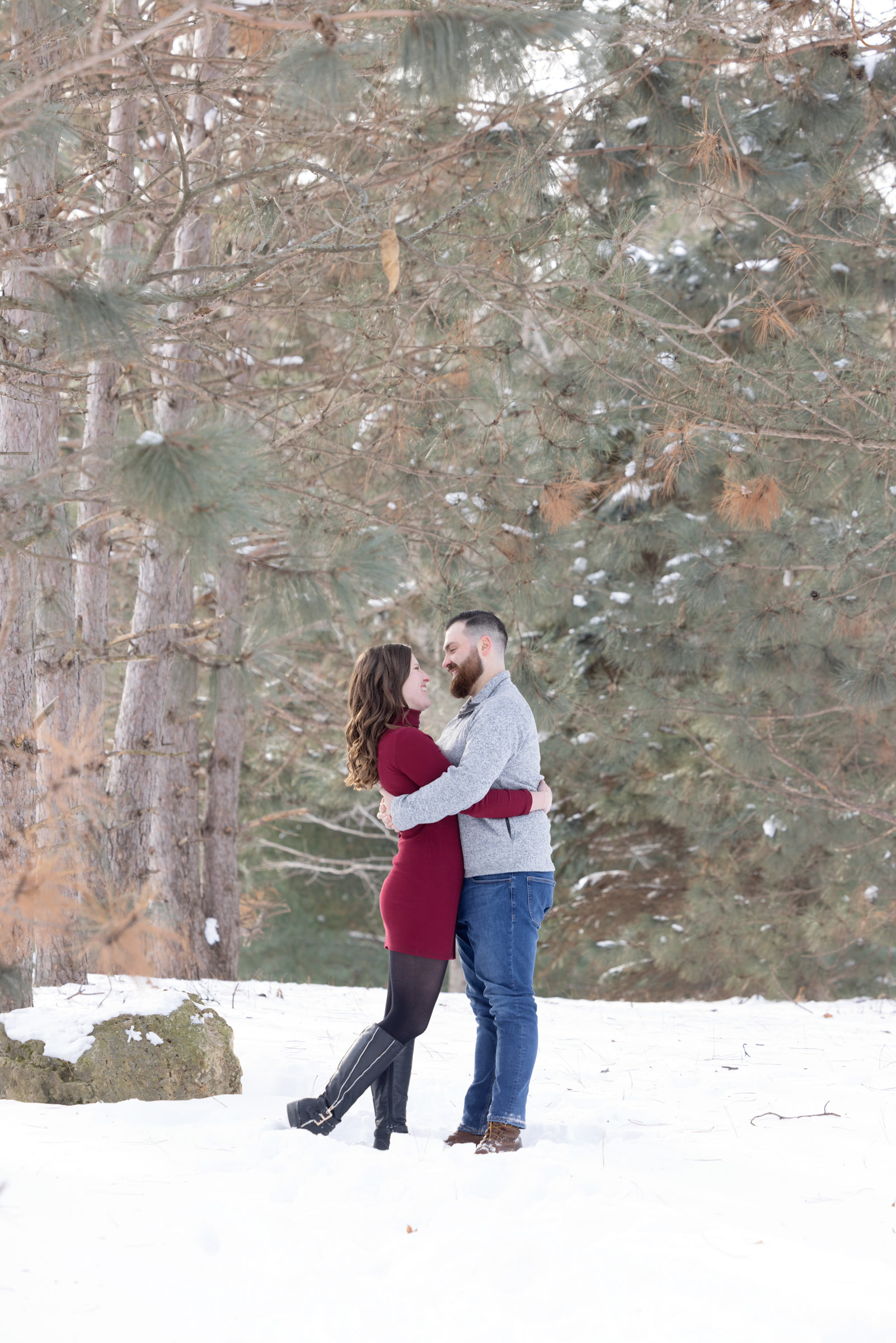 Engaged couple embracing outdoors during a winter engagement portrait session.
