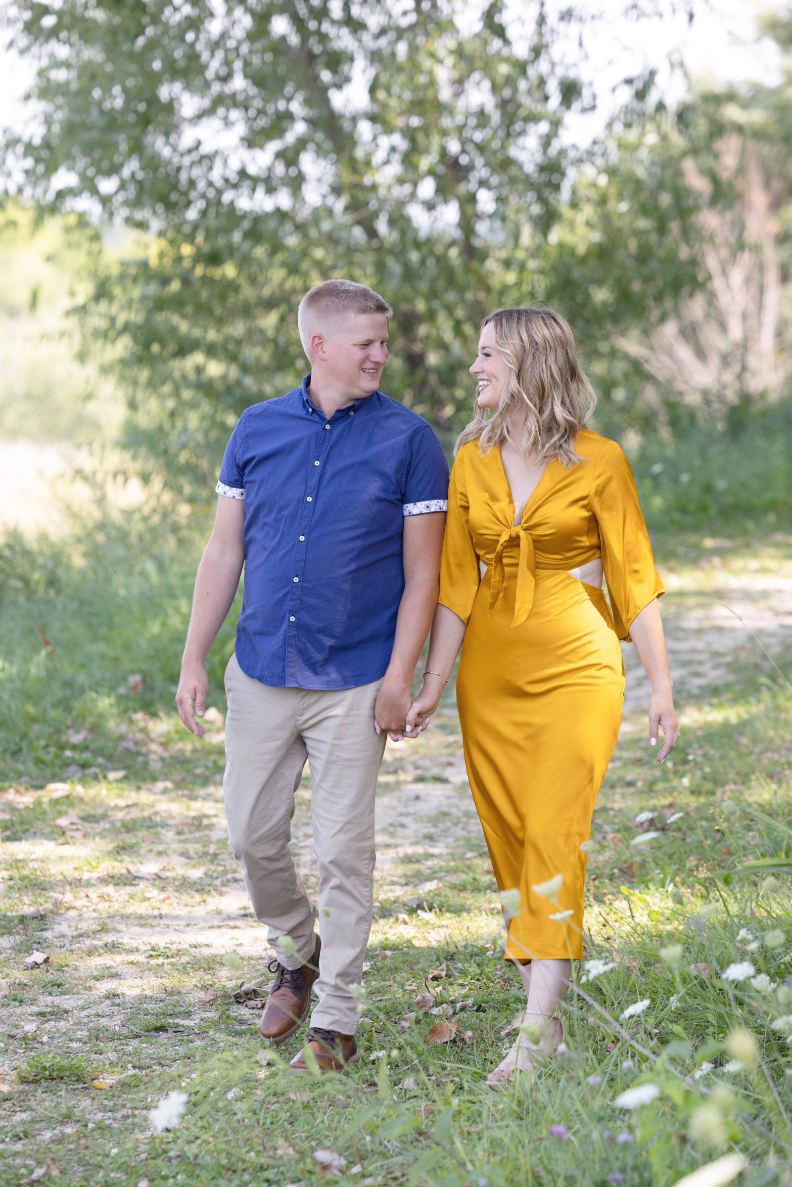 Engaged couple walking together outdoors during their engagement portrait session.