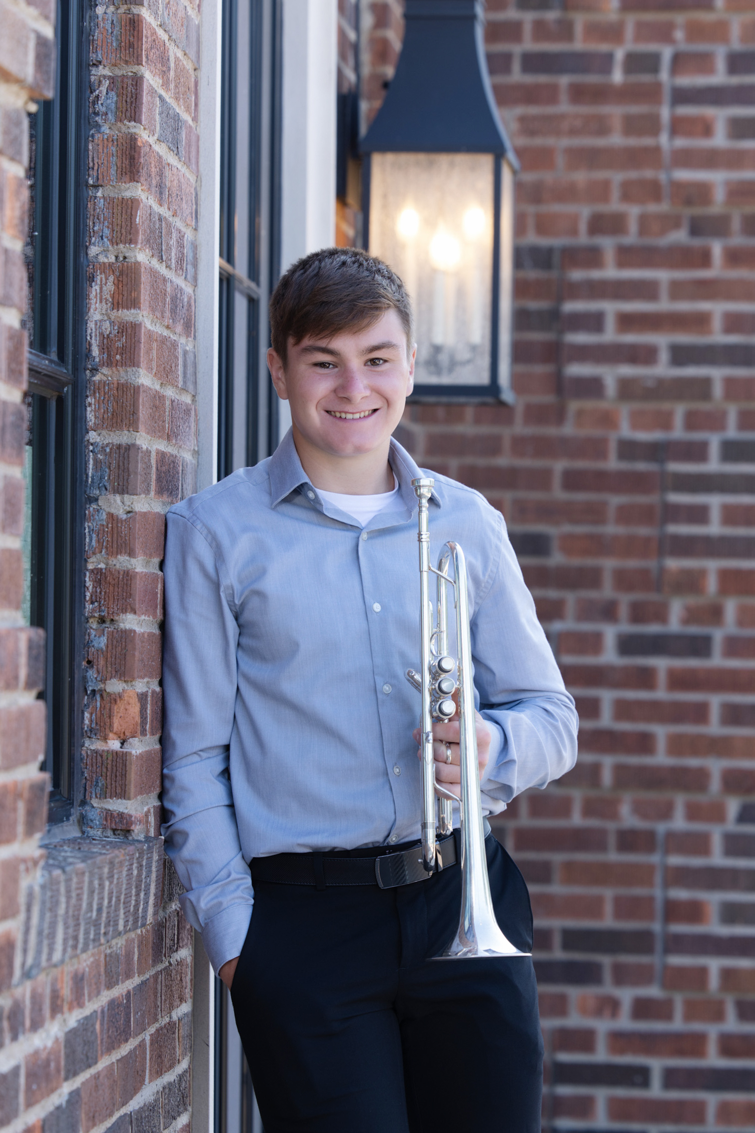 High school senior holding a musical instrument while standing outside a downtown building.