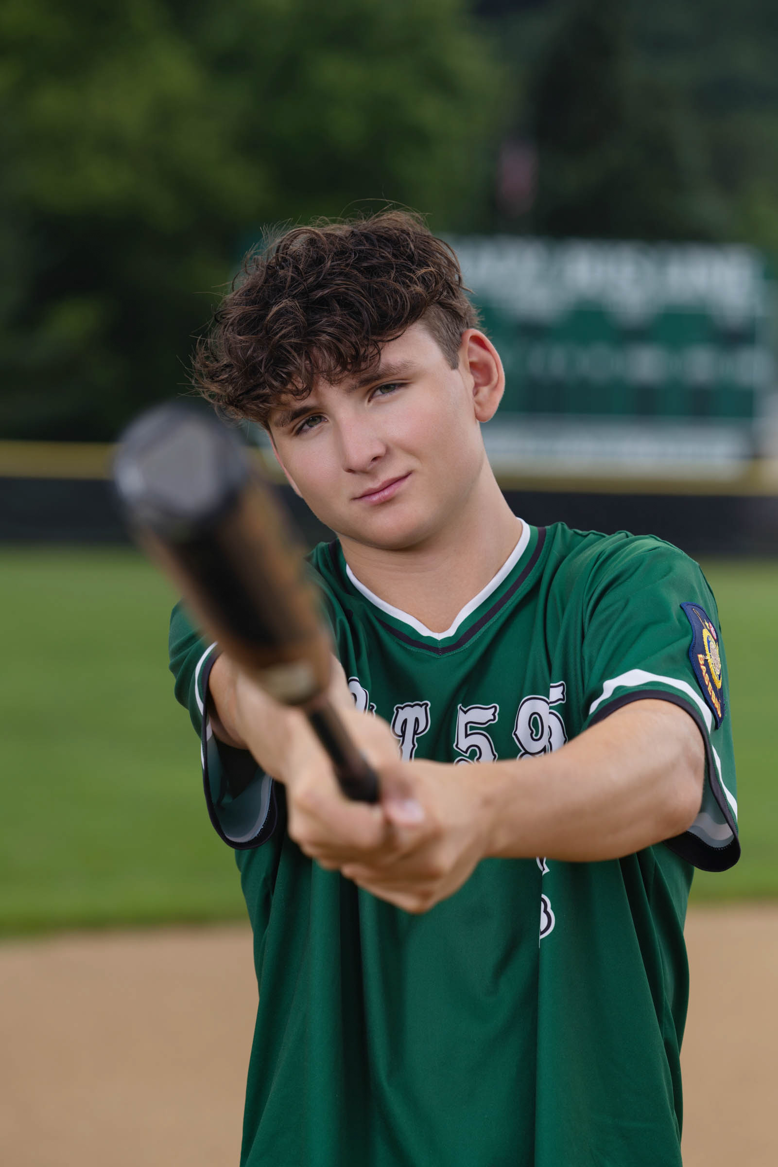 High school senior holding a baseball bat during an outdoor portrait session.