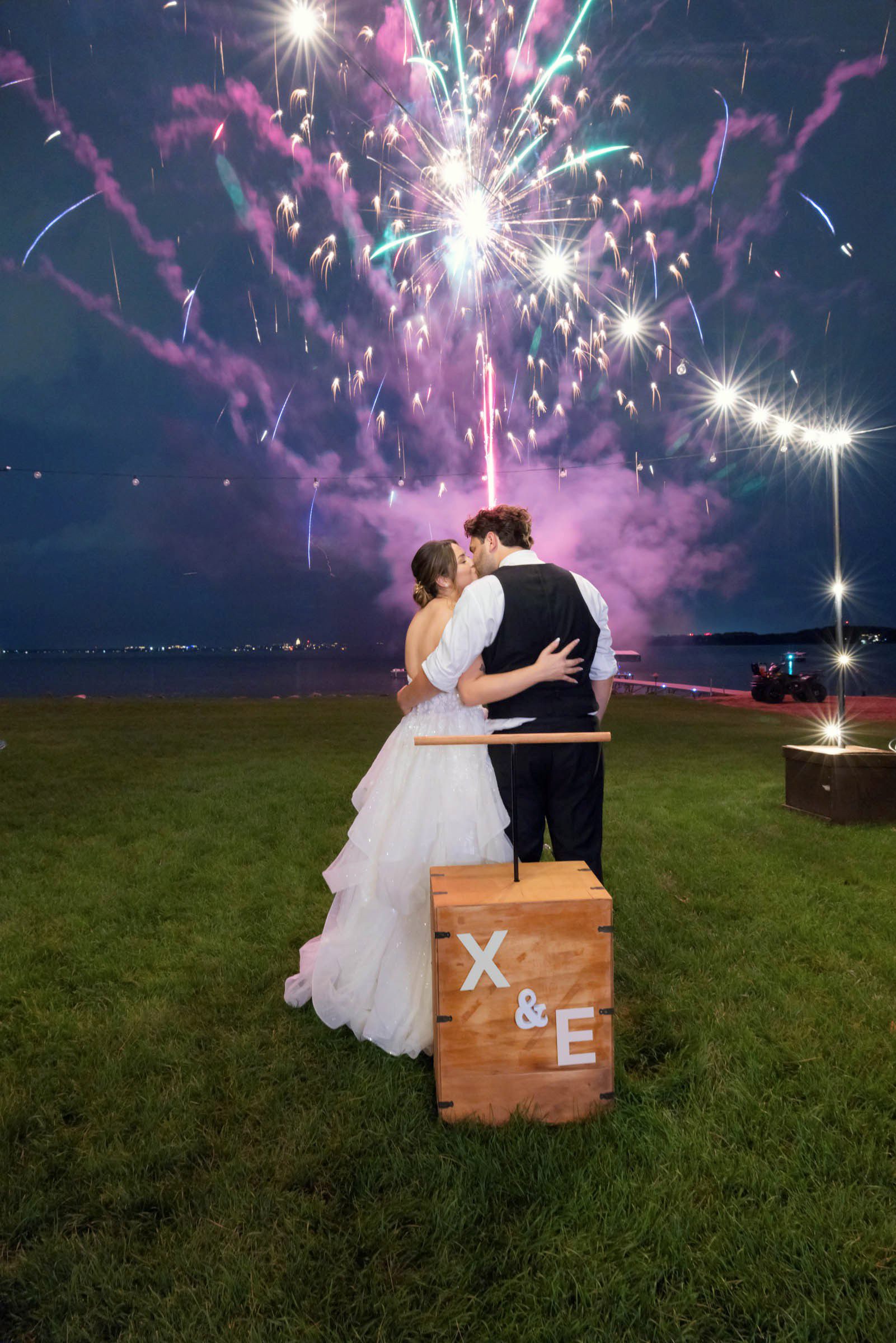 Bride and groom watching fireworks during their wedding celebration, representing the lasting memories preserved through albums and wall portraits.