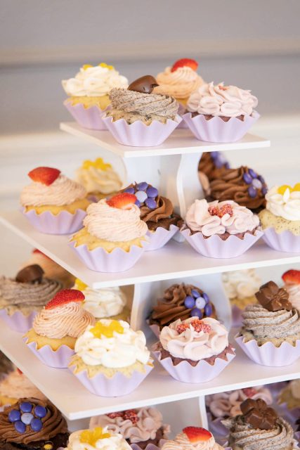 Display of cupcakes and desserts arranged on tiered stands at a wedding reception.