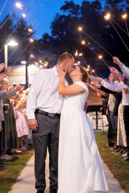 Bride and groom kissing during a sparkler exit at their wedding reception.